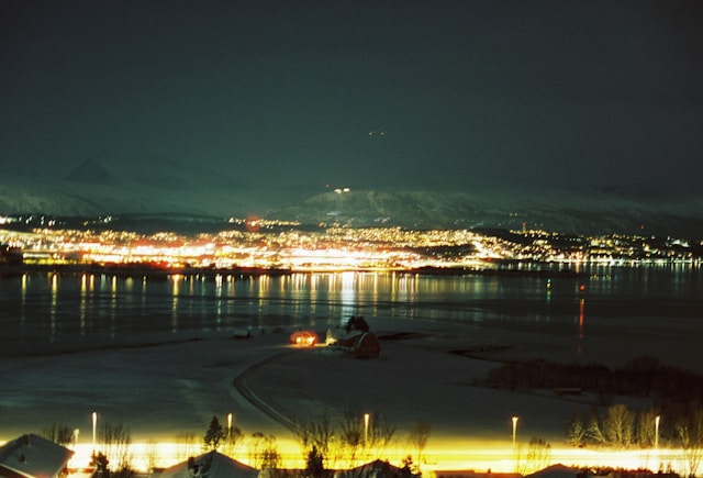 Nighttime cityscape lights shimmer across the water (Tromsø, Norway)