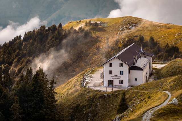 White building on a grassy mountain slope with trees (Monte Pizzoc, Fregona, Province of Treviso, Italy)