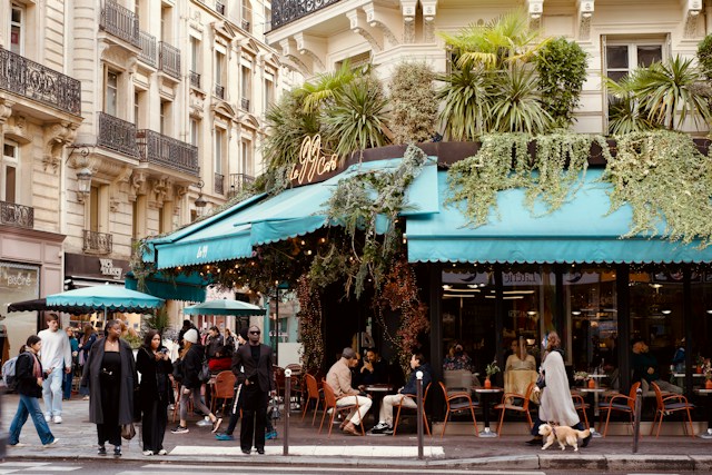 People dining at outdoor cafe with lush greenery, Paris France